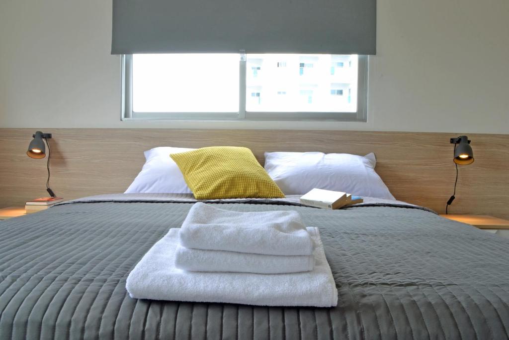1 cama con toallas encima y ventana en Athena Holiday Homes, en Limassol
