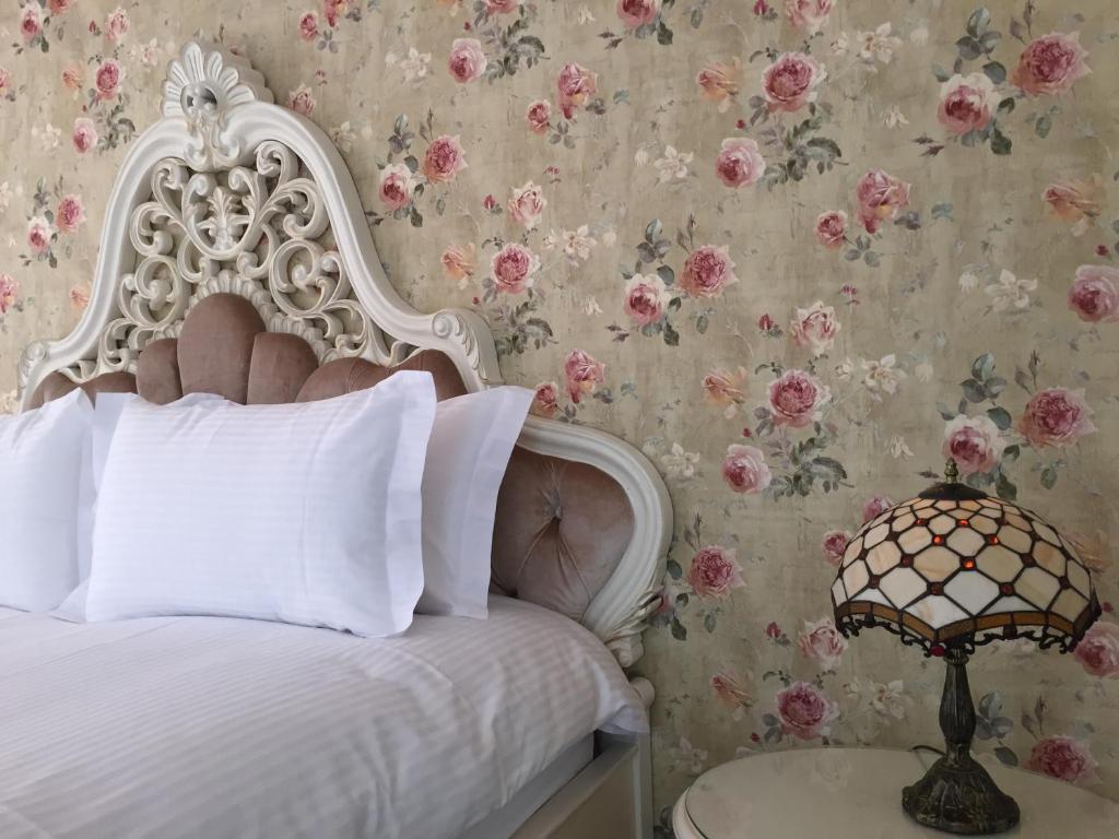 a bedroom with a white bed with a floral wallpaper at Bliss Bed and Breakfast in Yuchi