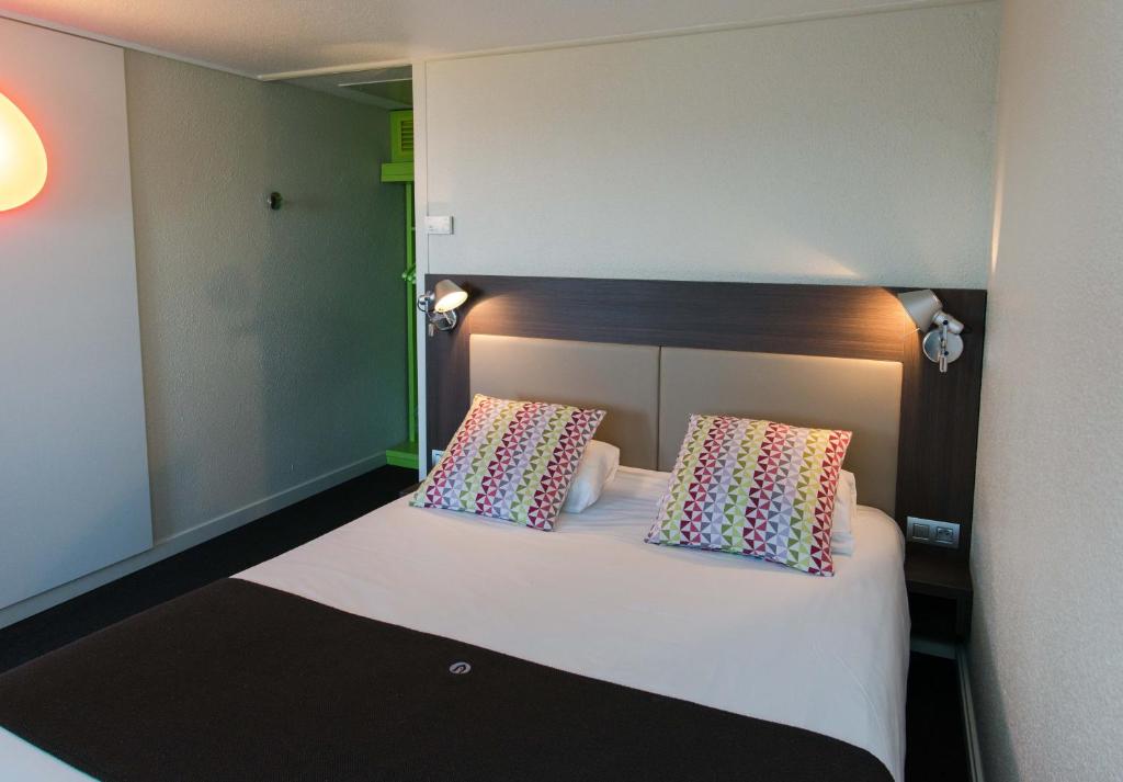 a room with a bed with two pillows on it at Campanile Agen in Agen