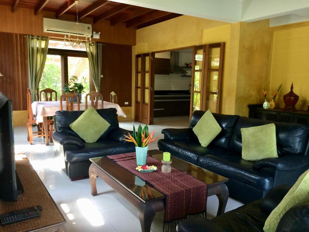 a living room with black leather couches and a coffee table at Symphony Villa in Nai Harn Beach