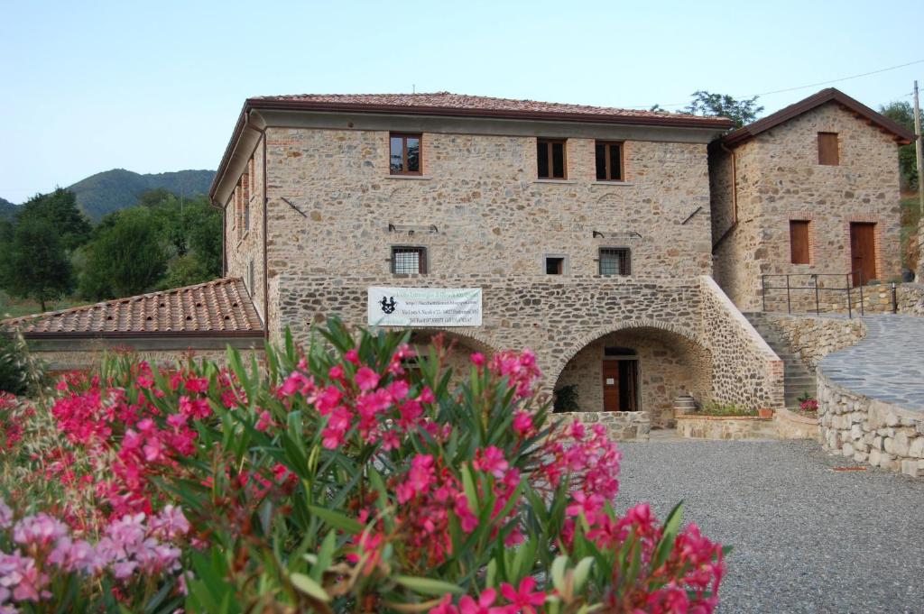 a stone building with pink flowers in front of it at Agriturismo LucchettiFerrari in Pontremoli