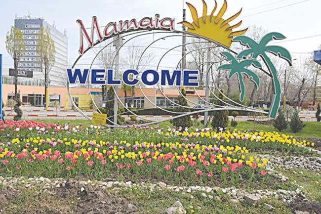 a sign for the marmite welcome in a garden of flowers at Apartament Mamaia Luna Park in Constanţa