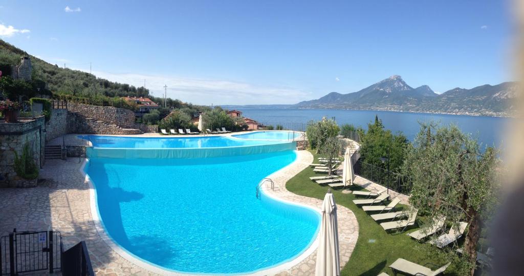 a large swimming pool next to a body of water at Casa Pina in Castelletto di Brenzone