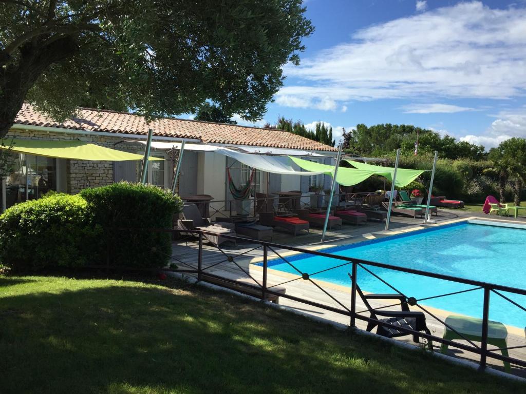 a swimming pool with umbrellas and a house at Maison des Algues in Rivedoux-Plage