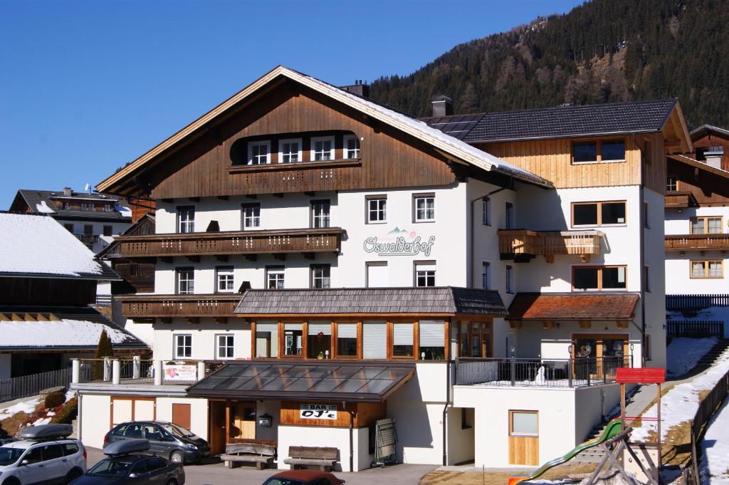 un grand bâtiment blanc avec un toit marron dans l'établissement Der Oswalderhof, à Obertilliach