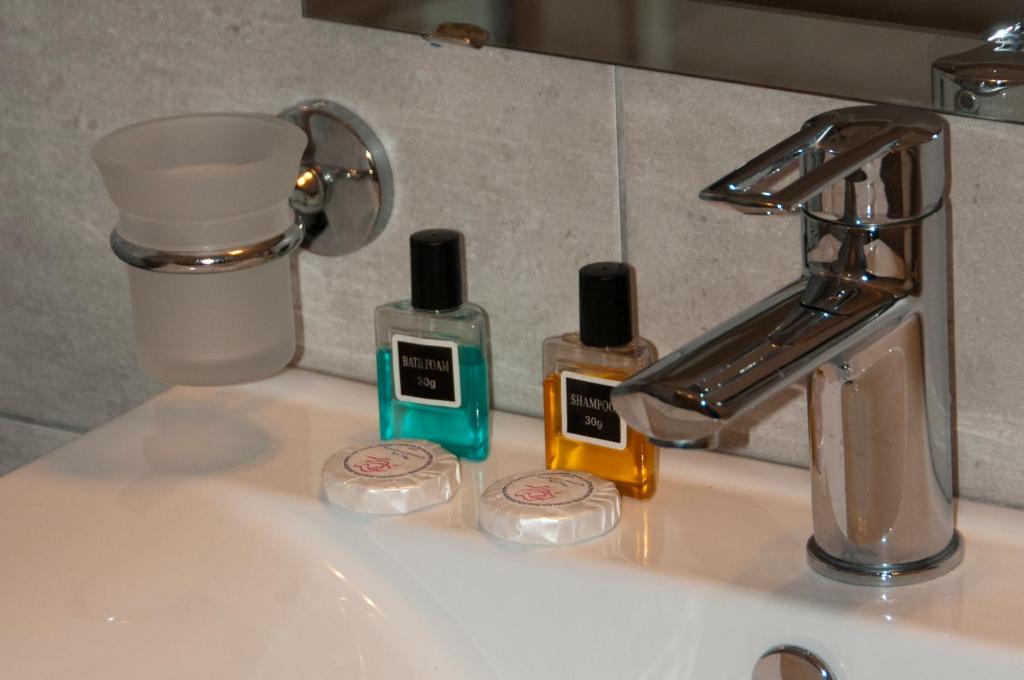 a bathroom sink with two bottles of soap and a faucet at Riviera Perdika Hotel in Perdika