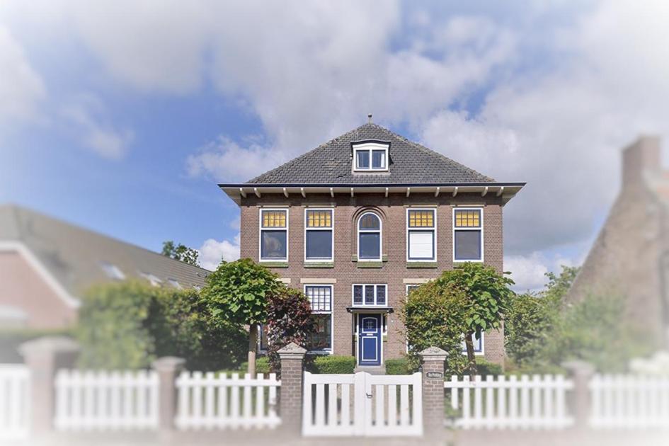 a large house with a white fence in front of it at Gasterij d'Ouwe Pastorie in Wolphaartsdijk