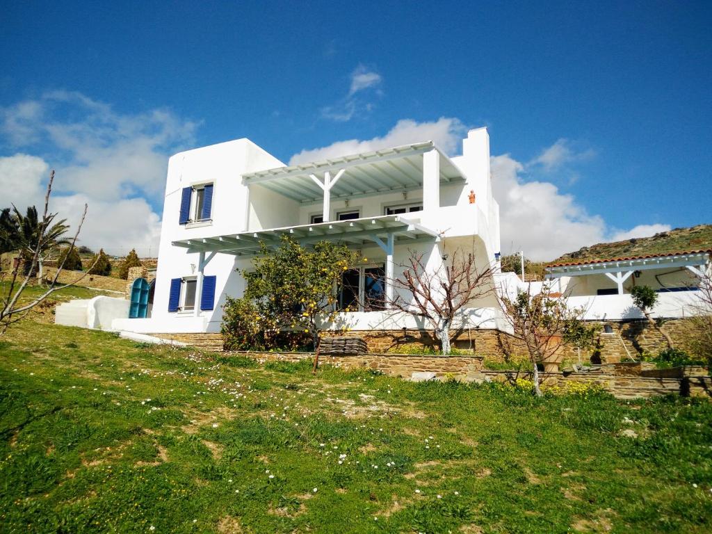 ein weißes Haus auf einem Hügel mit einem grünen Hof in der Unterkunft Villa Valentino in Gavrio