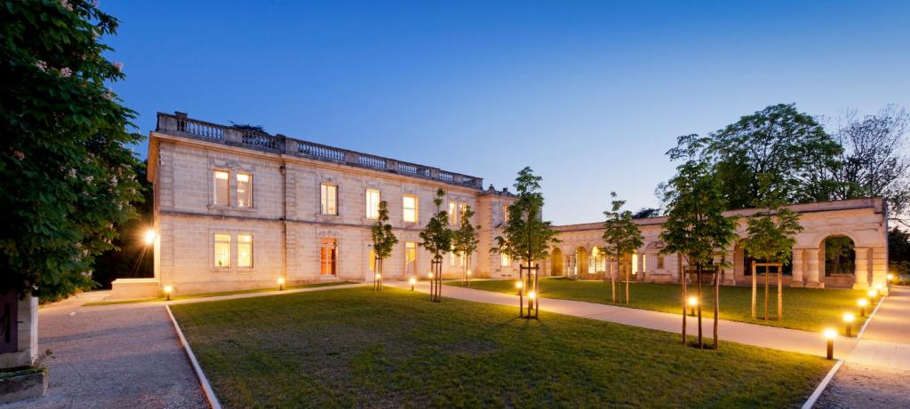- un grand bâtiment en briques avec des lumières dans la cour dans l'établissement Hôtel Château La Chèze - Bordeaux Floirac, à Floirac