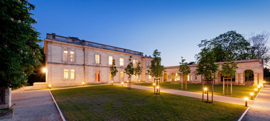 un grande edificio in mattoni con luci nel cortile di Hôtel Château La Chèze - Bordeaux Floirac a Floirac