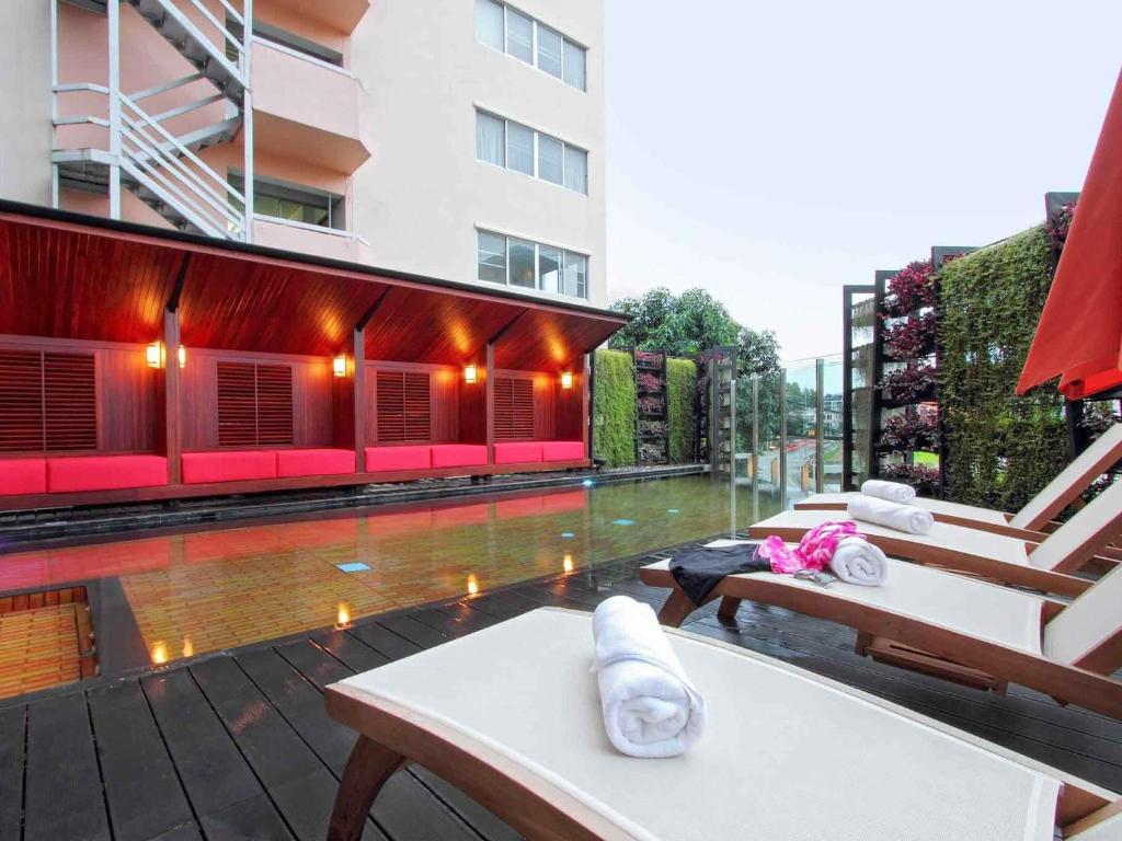 Loungers face a reflective pool beside a warmly lit red-walled terrace.