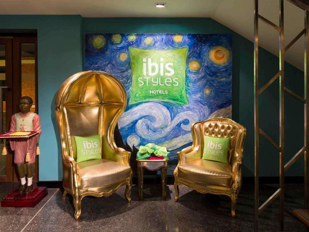 A themed lobby seating nook with two ornate gold chairs beside hotel artwork.