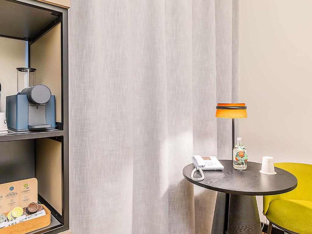 A compact in-room work and refreshment corner with a round table and yellow chair.
