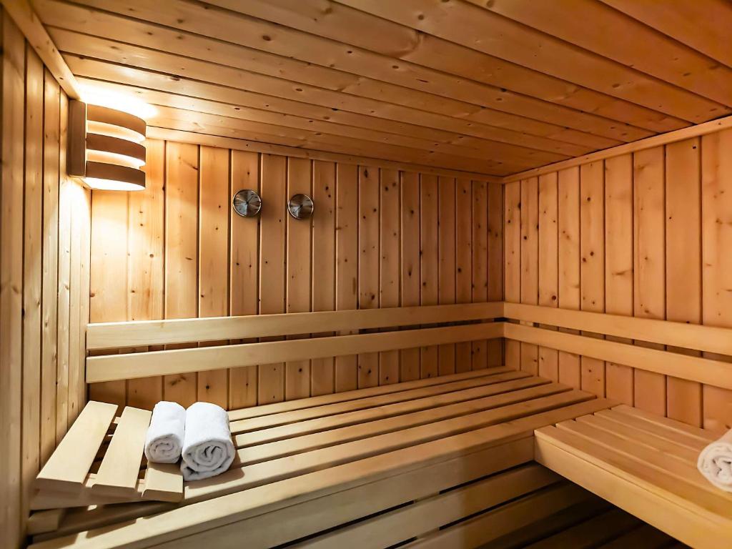 A wood-lined sauna with tiered benches and rolled towels.