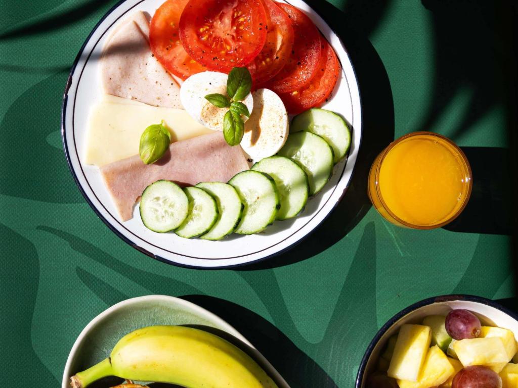 A styled breakfast plate with fresh vegetables, fruit and orange juice.