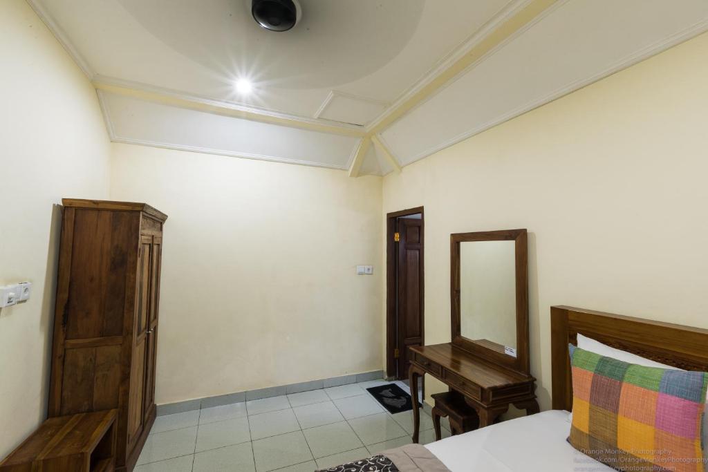 a bedroom with a bed and a mirror and a table at Sudiana House in Ubud