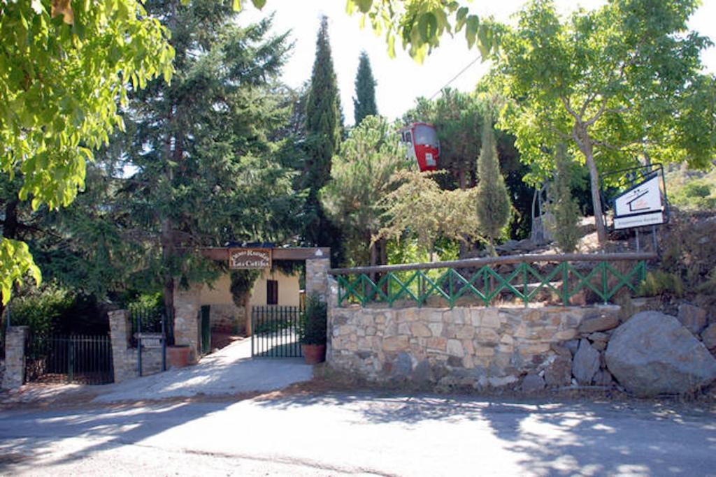 a house with a stone wall and a fence at Telecabina las Catifas in Güéjar-Sierra