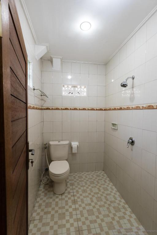 a bathroom with a toilet and a tile floor at Sudiana House in Ubud