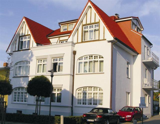 ein großes weißes Haus mit rotem Dach in der Unterkunft Appartementhaus Plueckhahn in Kühlungsborn