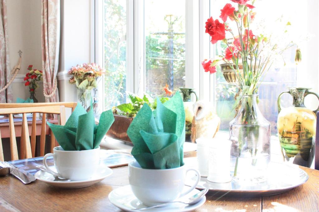 a table with two cups with flowers in them at The Limes in Stow on the Wold