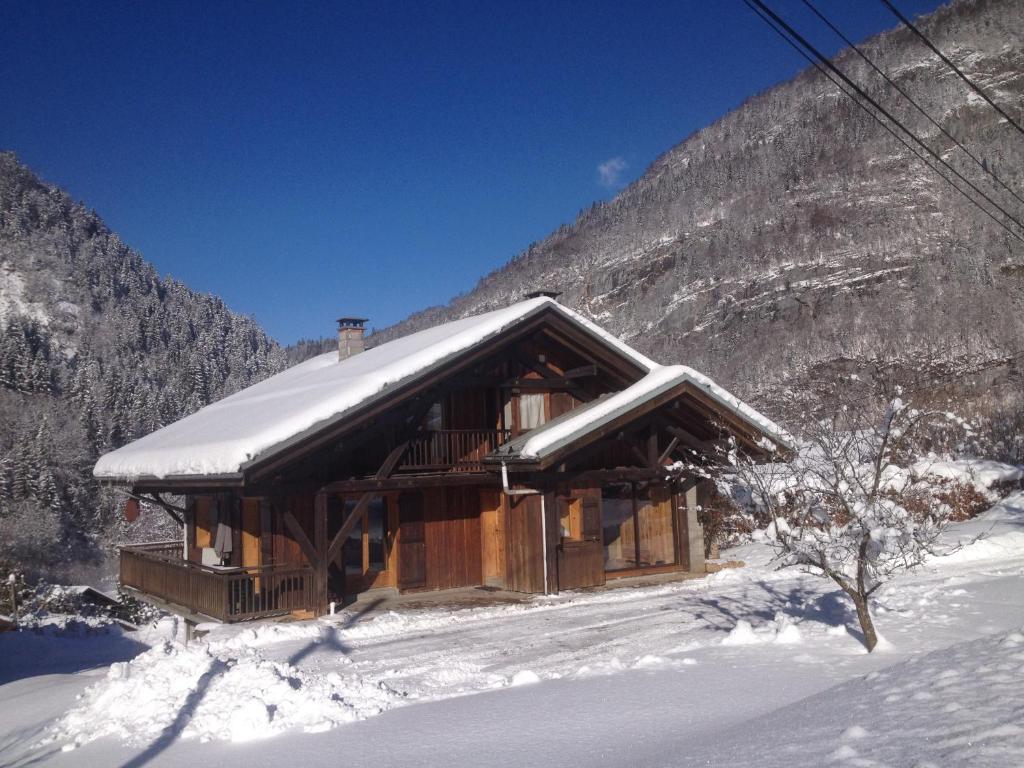 una baita di tronchi nella neve con una montagna di Chalet Narcisse a Sixt