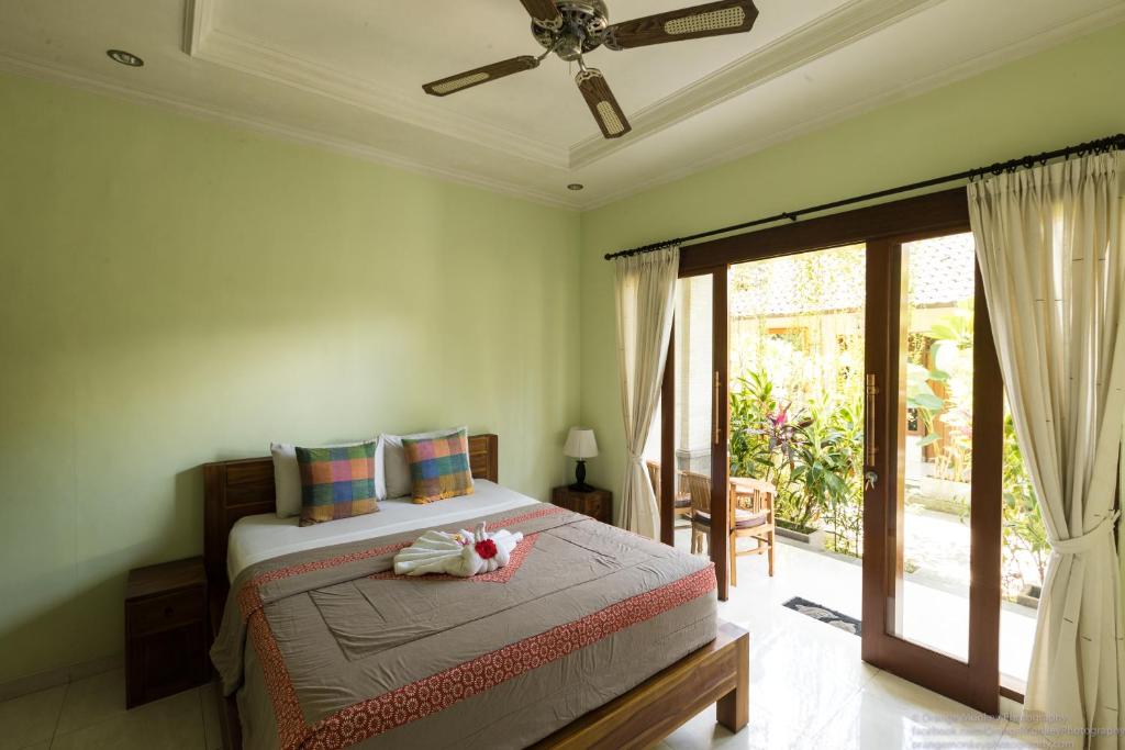 a bedroom with a bed with a ceiling fan at Sudiana House in Ubud