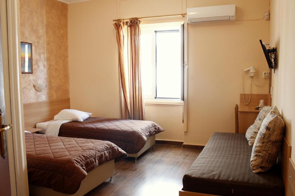 ピレウスにあるエレクトラ ホテル ピレウスのベッド2台と窓が備わる小さな客室です。
