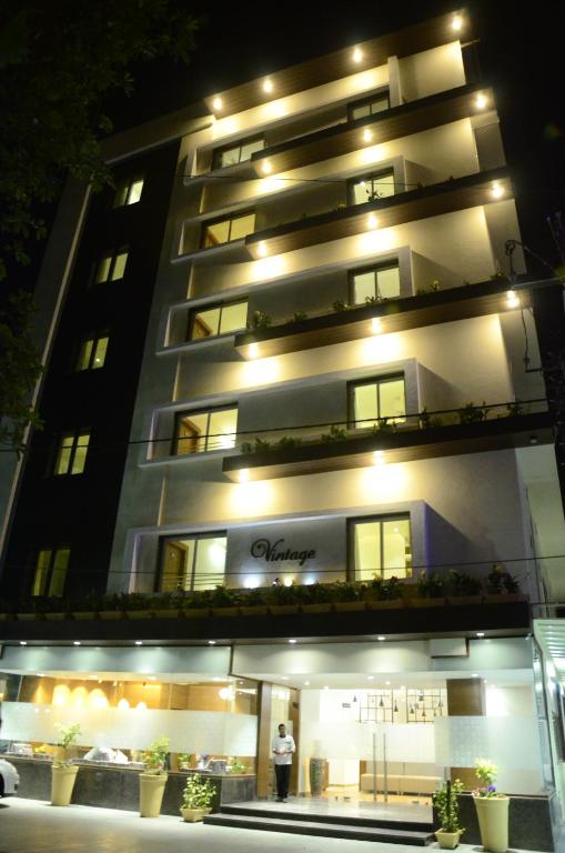 a man standing in front of a building at night at Hotel Vintage in Vadodara