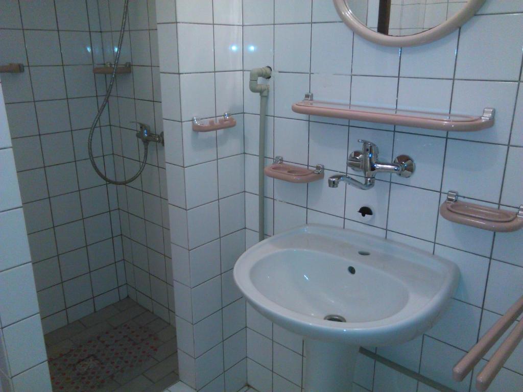 y baño de azulejos blancos con lavabo y ducha. en Penzion U Jezu Dobronice, en Dobronice