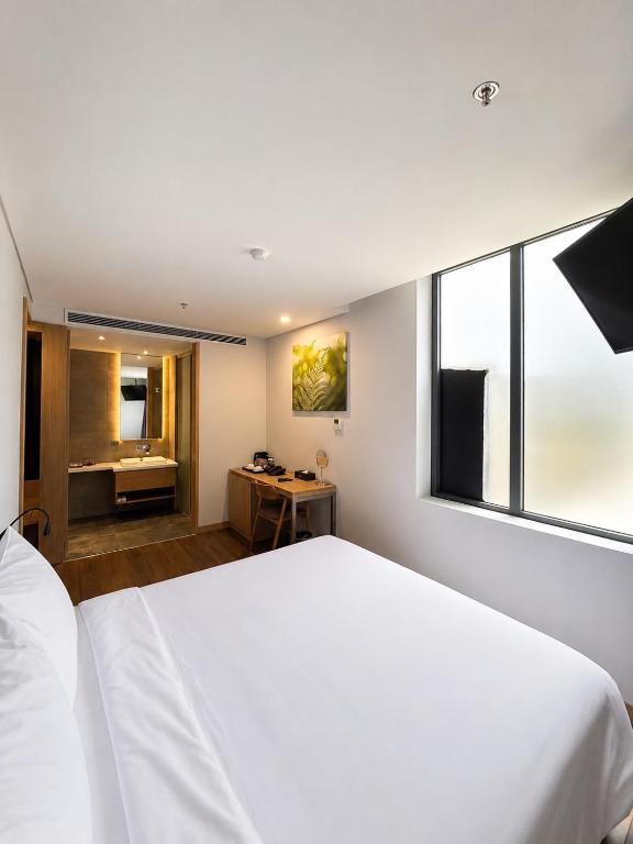 A bedroom view showing the bed, vanity area, desk and glazed bathroom entrance.