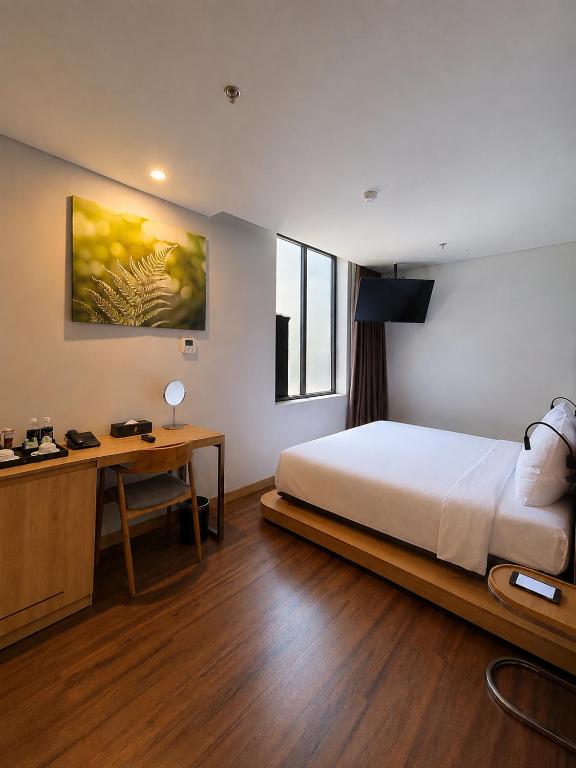 A spacious-looking bedroom with a large bed, work desk and beverage station.