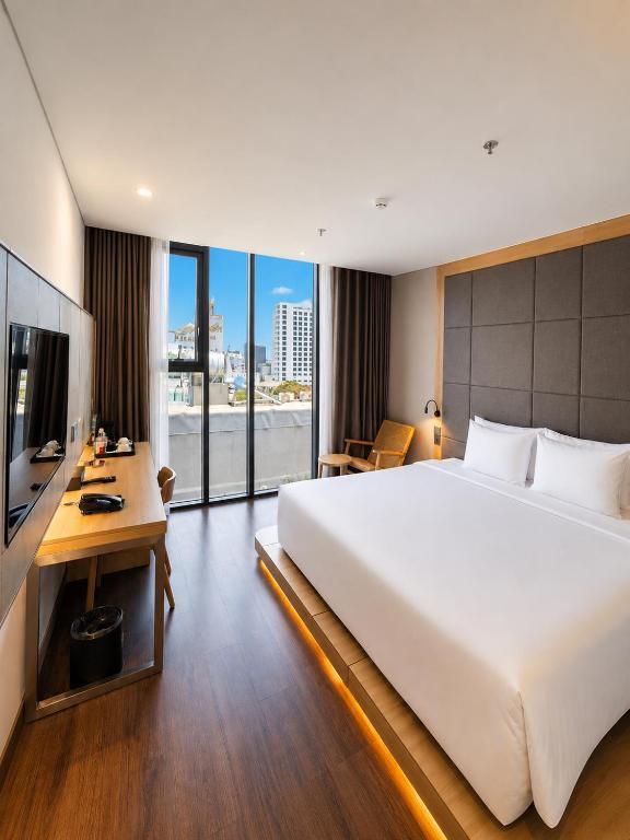 A polished city-facing bedroom with a large bed, desk and floor-to-ceiling windows.