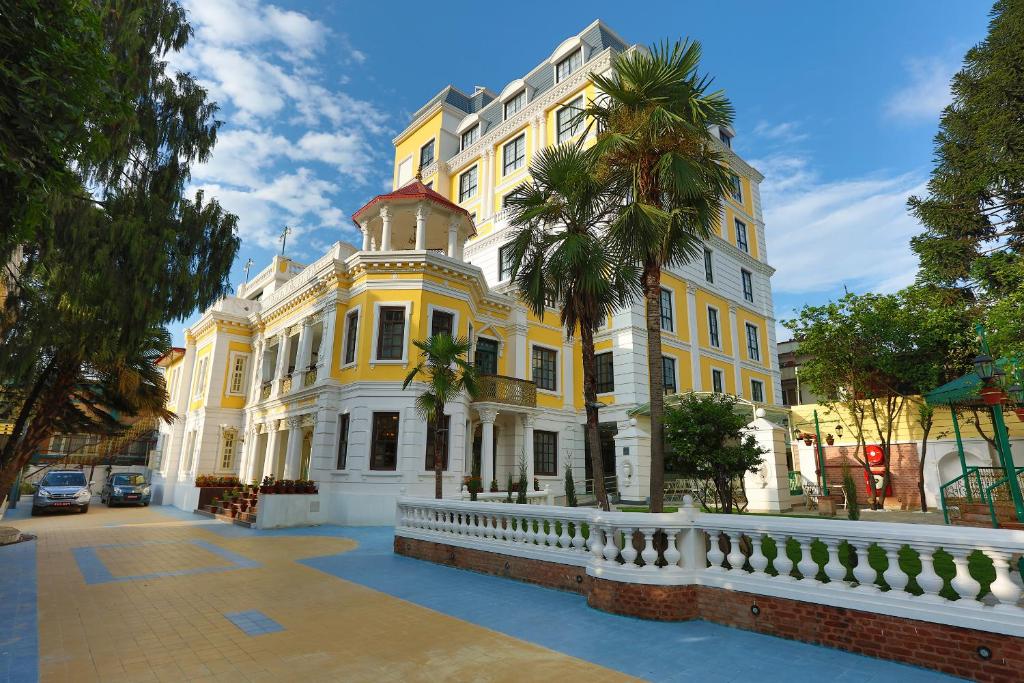 un edificio blanco y amarillo con una palmera delante en Maya Manor Boutique Hotel by KGH Group, en Katmandú
