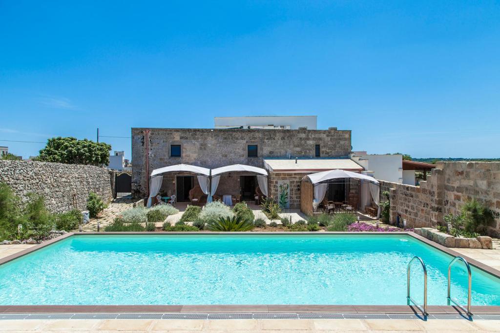 a swimming pool in front of a house with a building at Masseria Palane in Patù