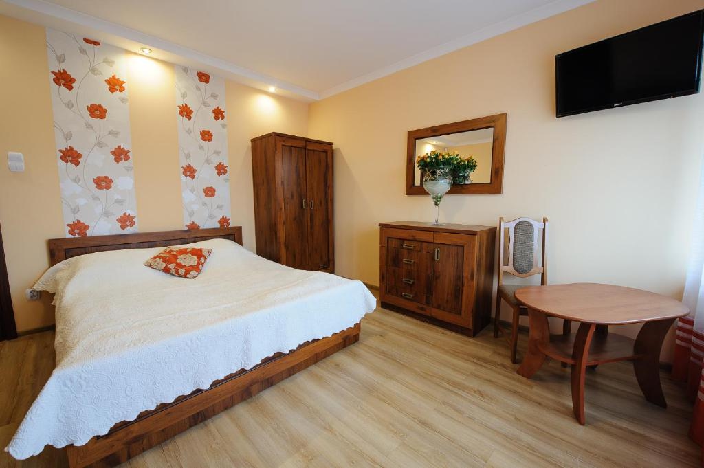 1 dormitorio con cama, mesa y TV en Pokoje i apartamenty IWONA, en Ciechocinek