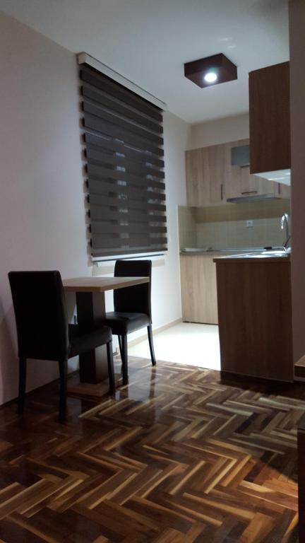 a dining room with a table and chairs and a kitchen at Apartman Ristanovic in Banja Koviljača