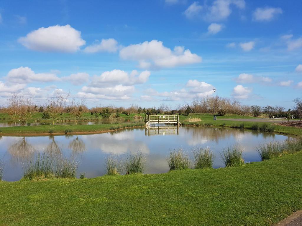 einen Teich in einem Park mit einer Bank in der Mitte in der Unterkunft Sycamore Farm Park in Burgh le Marsh