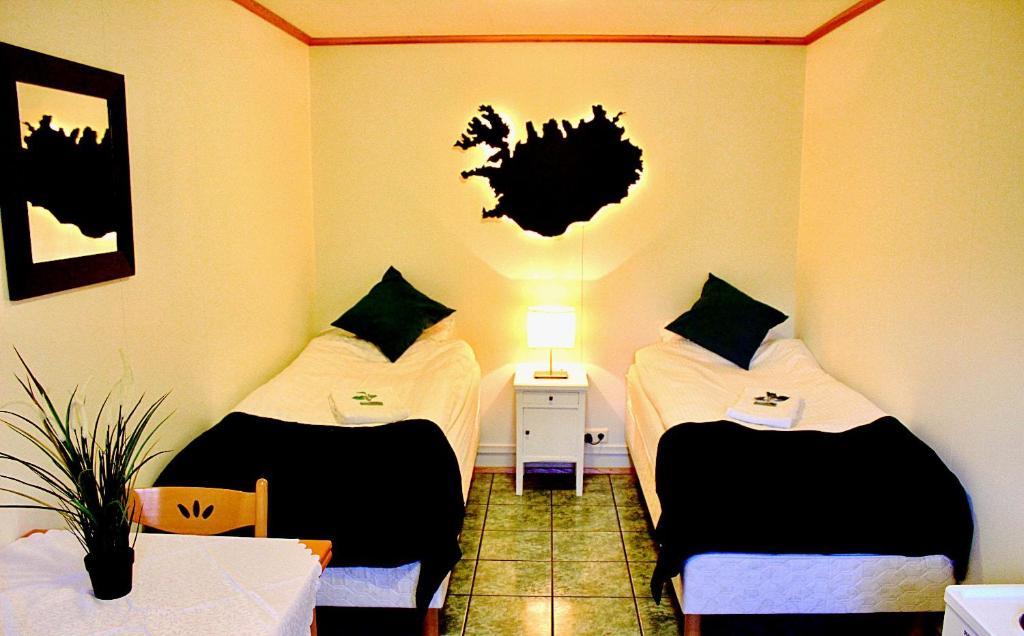ヴェストマン諸島にあるGuesthouse Árnýのベッド2台、テーブル、ランプが備わる客室です。