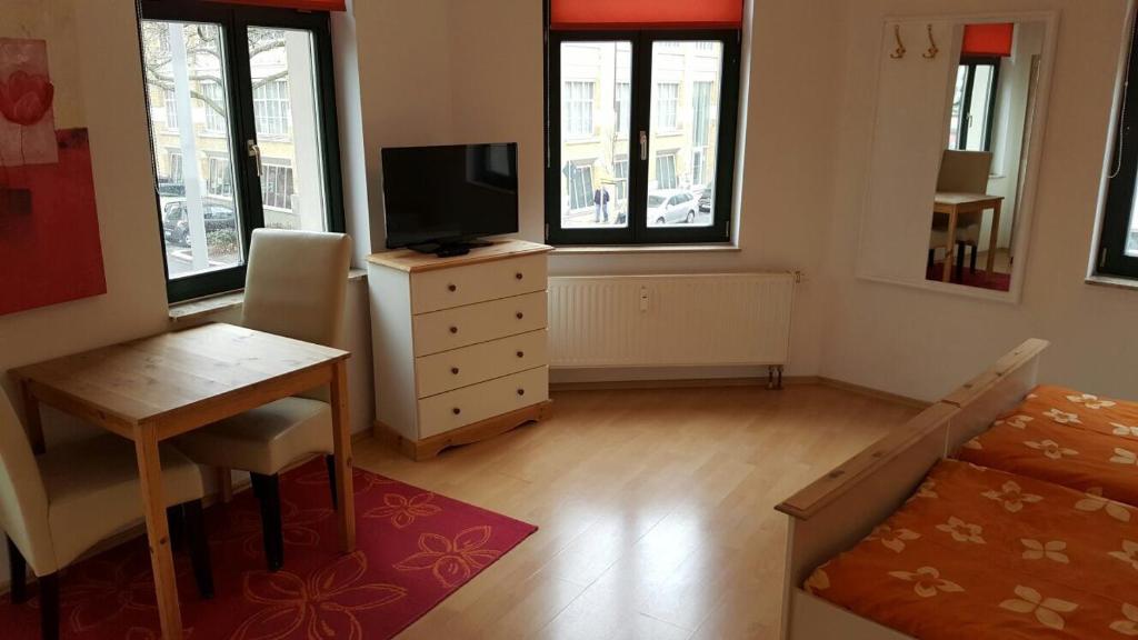 a living room with a television and a table and a desk at Internationales Gästehaus Leipzig in Leipzig