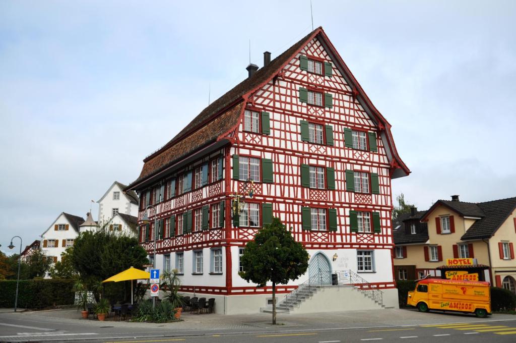un bâtiment rouge et blanc au coin d'une rue dans l'établissement Gasthof Zur Traube, à Roggwil