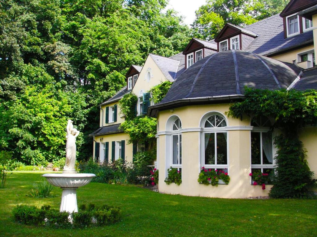 una casa grande con una estatua en el patio en Hotel & Restaurant Bellevue Schmölln, en Schmölln