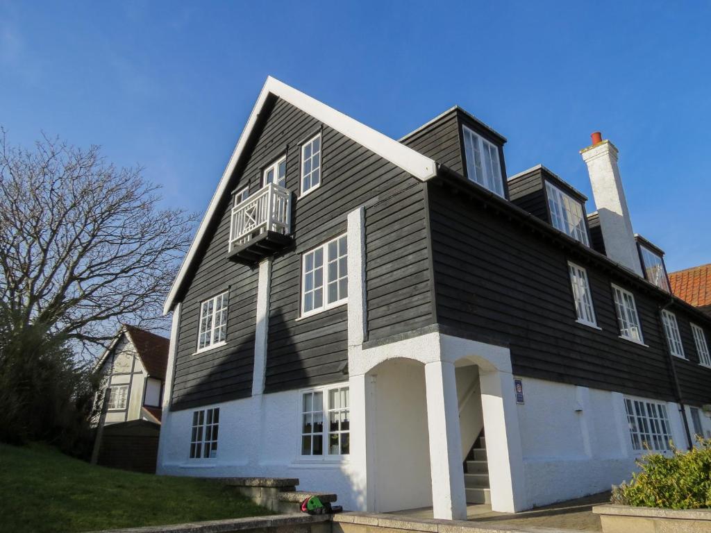 uma grande casa a preto e branco com uma varanda em Ogilvie Lodge Apartment em Thorpeness