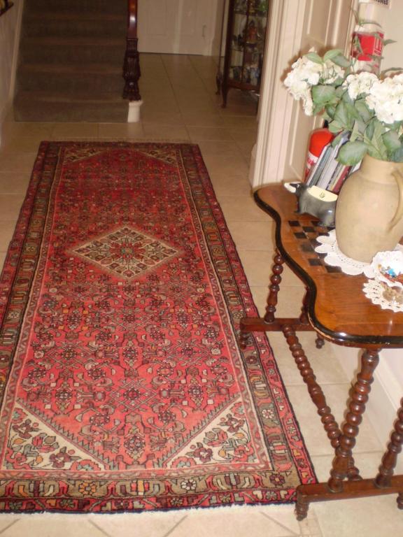 a room with a red rug on a floor with a table at Badger Towers in Cheltenham