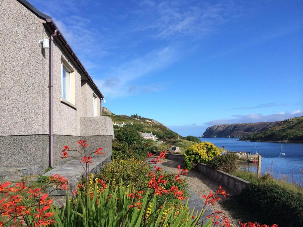 a house with a view of the water and flowers at Cuckoos Rock in Graver