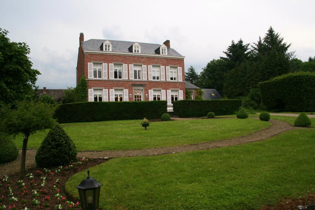 una gran casa de ladrillo con un patio verde en La Régie de Franc-Warêt, en Franc-Waret