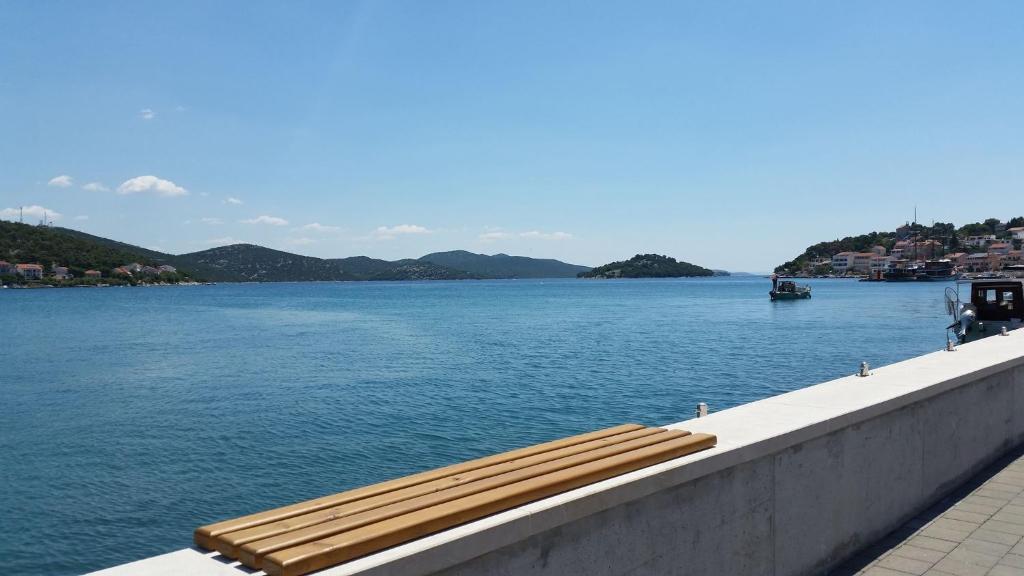 a couple of benches sitting on the edge of a body of water at Apartments Marin in Tisno