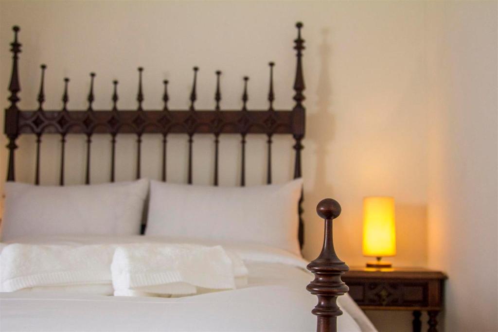 a bed with a wooden headboard and a table with a lamp at Braga Sarmiento Apartment in Braga