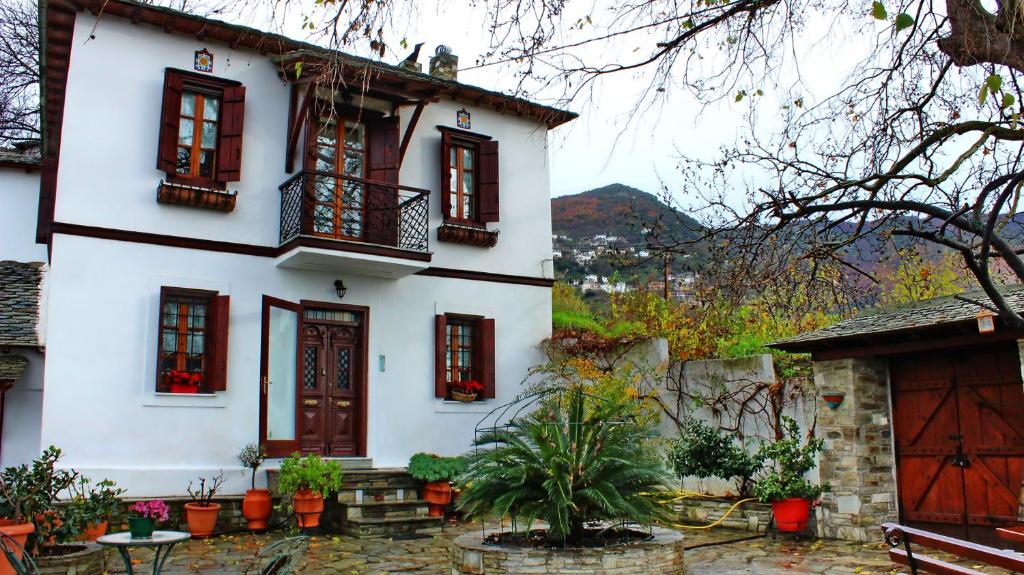 a white house with red windows and a balcony at Archontiko Stafylopati in Makrinitsa