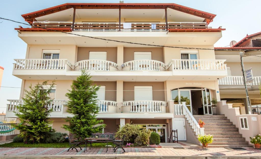 - un grand bâtiment avec des balcons et des tables en face dans l'établissement Porto Daliani, à Paralia Katerinis