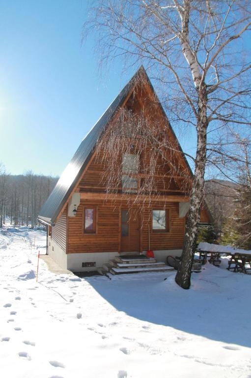 a log cabin in the snow with a tree at Holiday Home Edi in Delnice